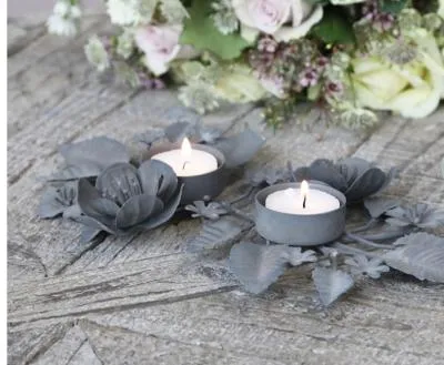 Antique zinc tealight holder with ornate leaves.