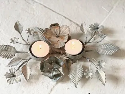 Antique zinc tealight holder with ornate leaves.